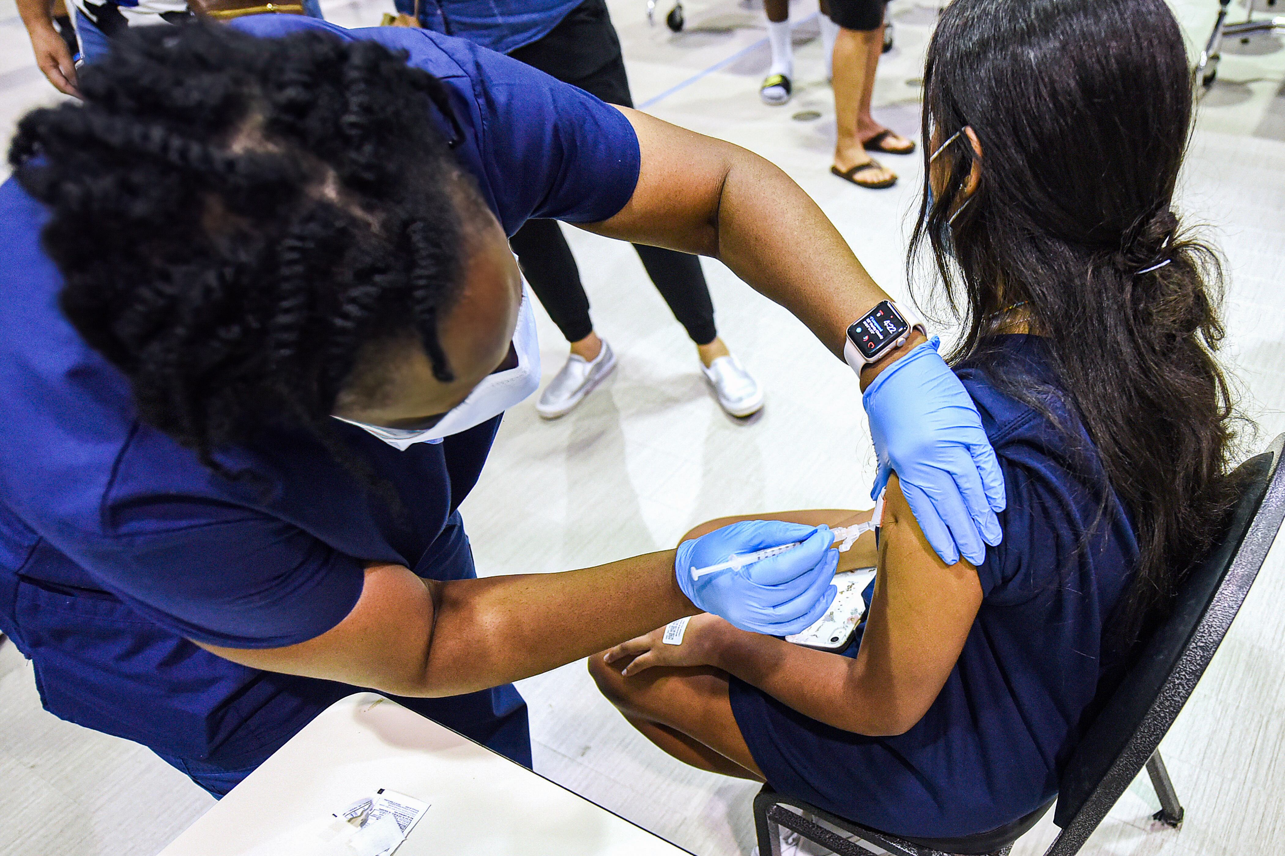 A nurse gives a dose of the Pfizer COVID vaccine to a teenage girl.