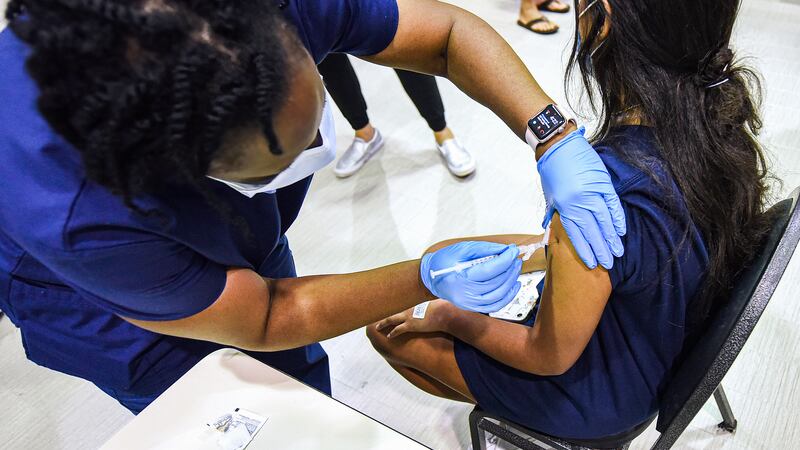 A nurse gives a dose of the Pfizer COVID vaccine to a teenage girl.