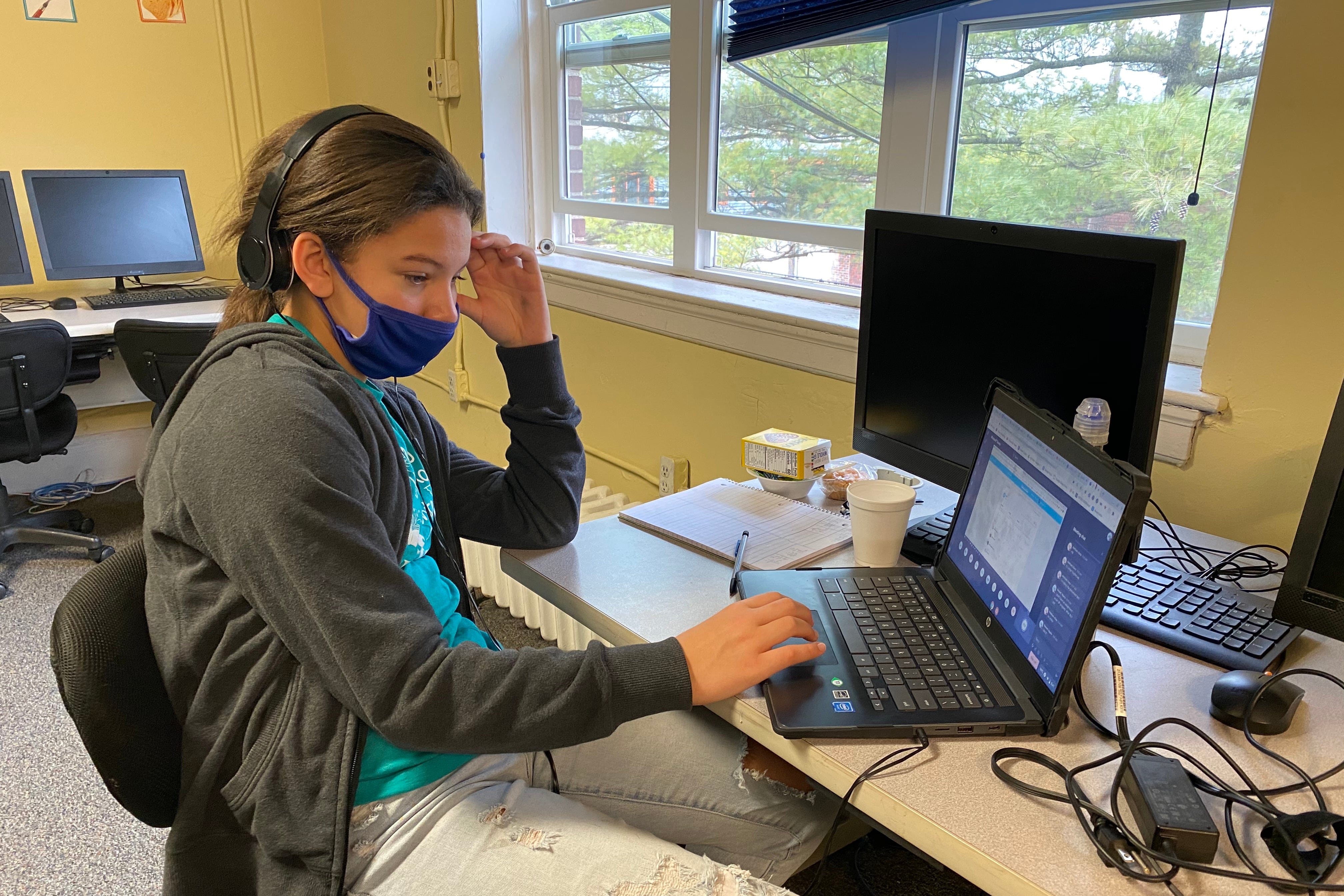 A student is sitting in a chair. The student is working on classwork from a laptop in virtual class at the Christamore House in Indianapolis, Ind.