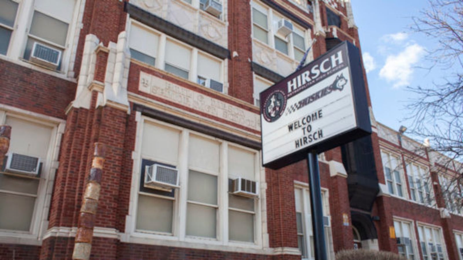 A sign in front of a school facade says “Welcome to Hirsch.” 