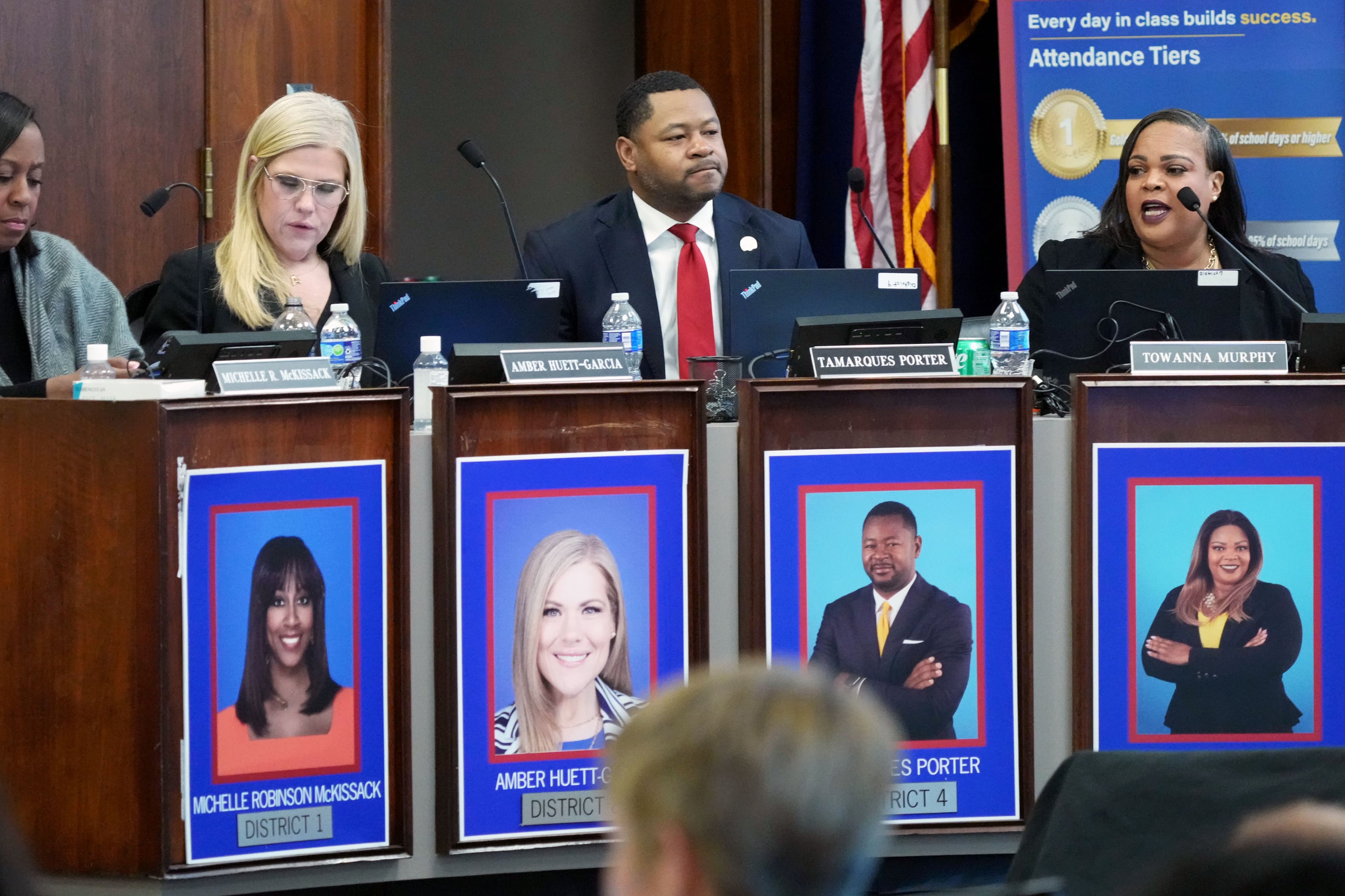 A photograph of four adults sitting at a table in a large conference room.