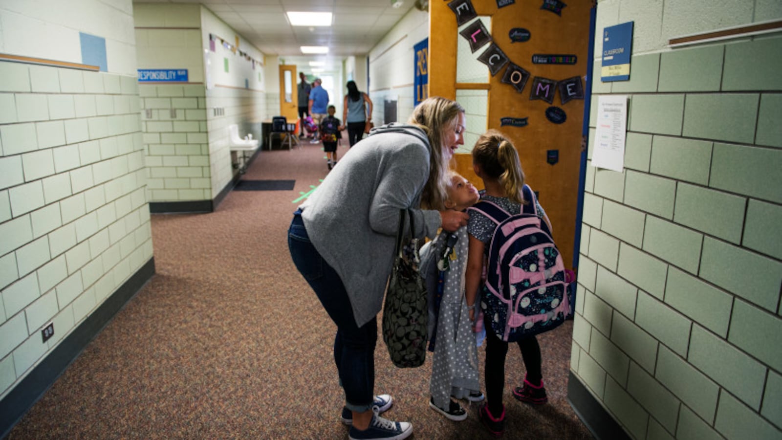 Mae Simpson leans down to talk to her daughter Stella before dropping her off for her first day of third grade in Arvada.