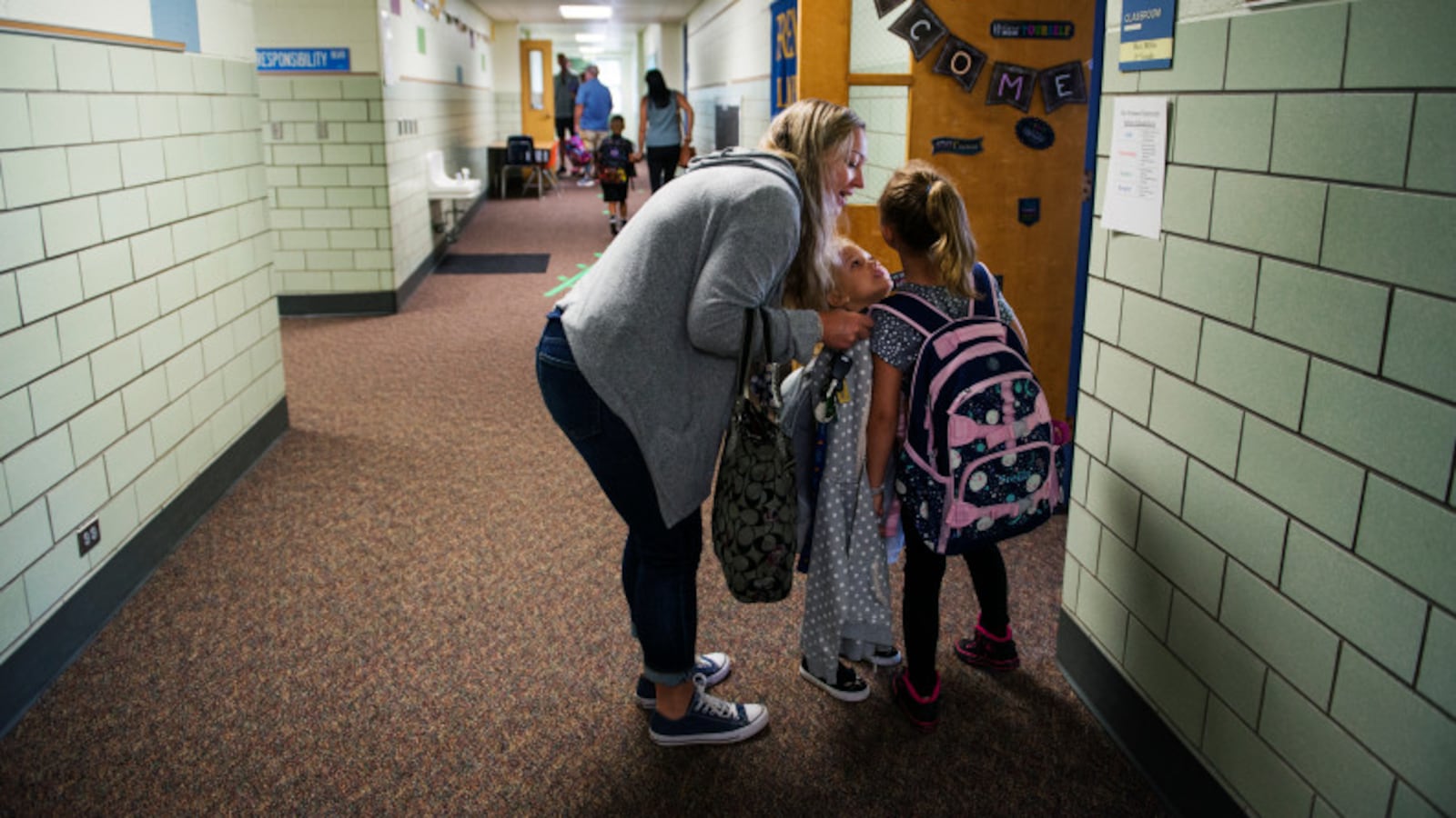 Mae Simpson leans down to talk to her daughter Stella before dropping her off for her first day of third grade in Arvada.