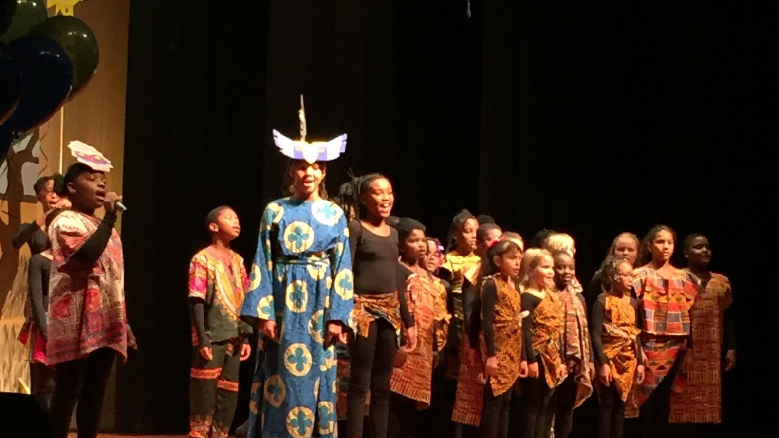 Fifth grader Arael Stigler (left with the microphone) performs the role of Rafinki from the musical The Lion King.