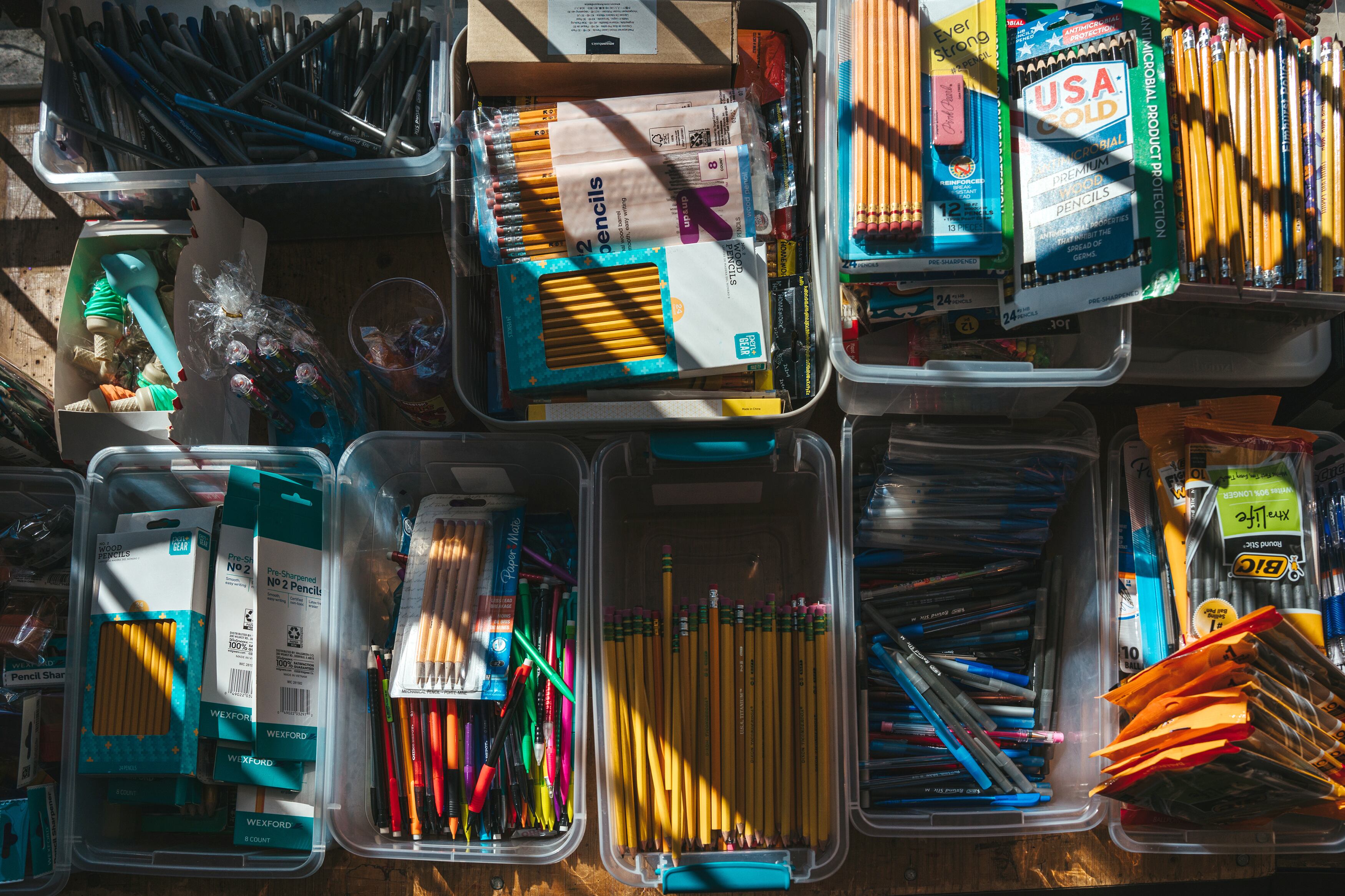 A table full of school supplies in different plastic containers.