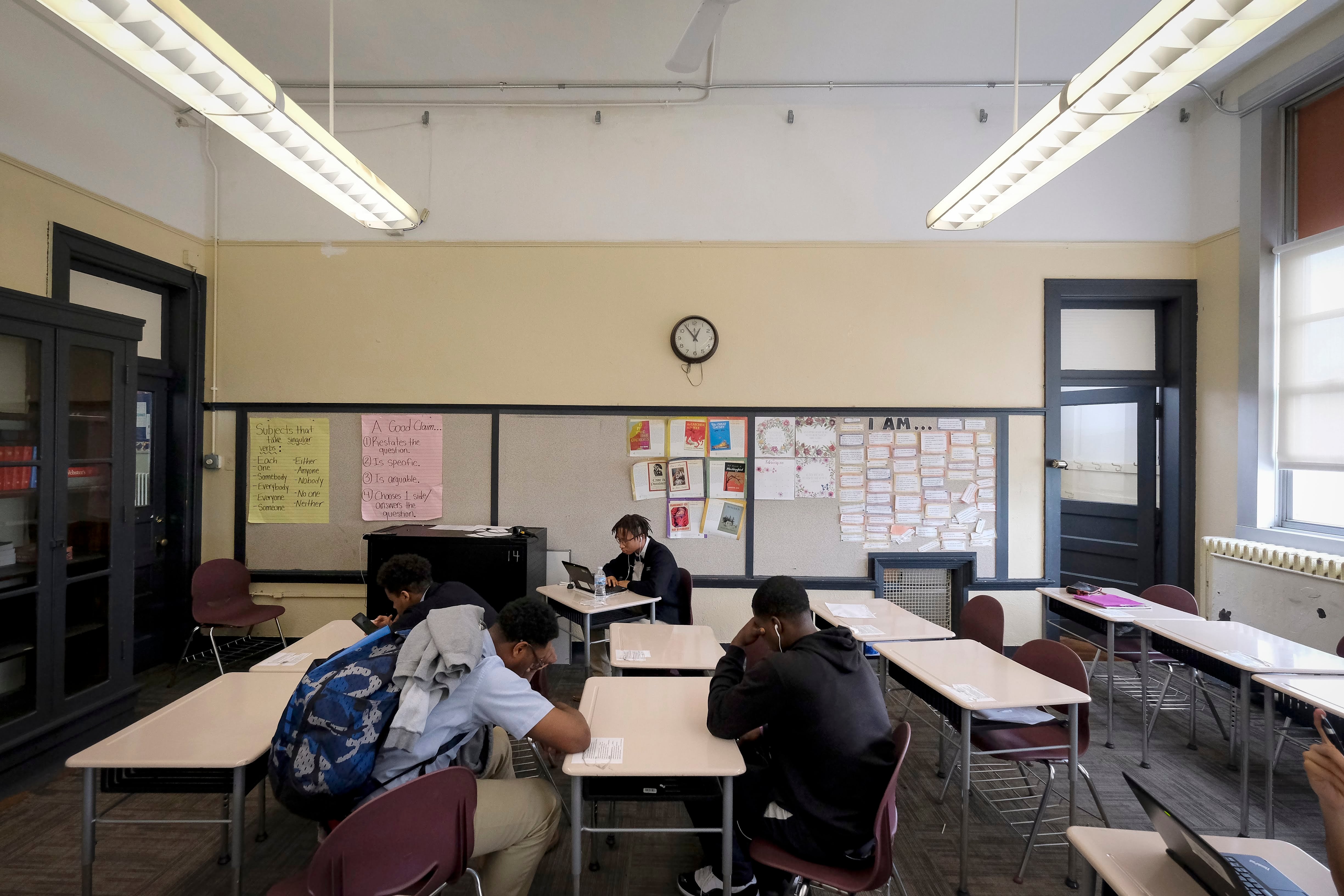 Four or five male students sit looking down in a classroom