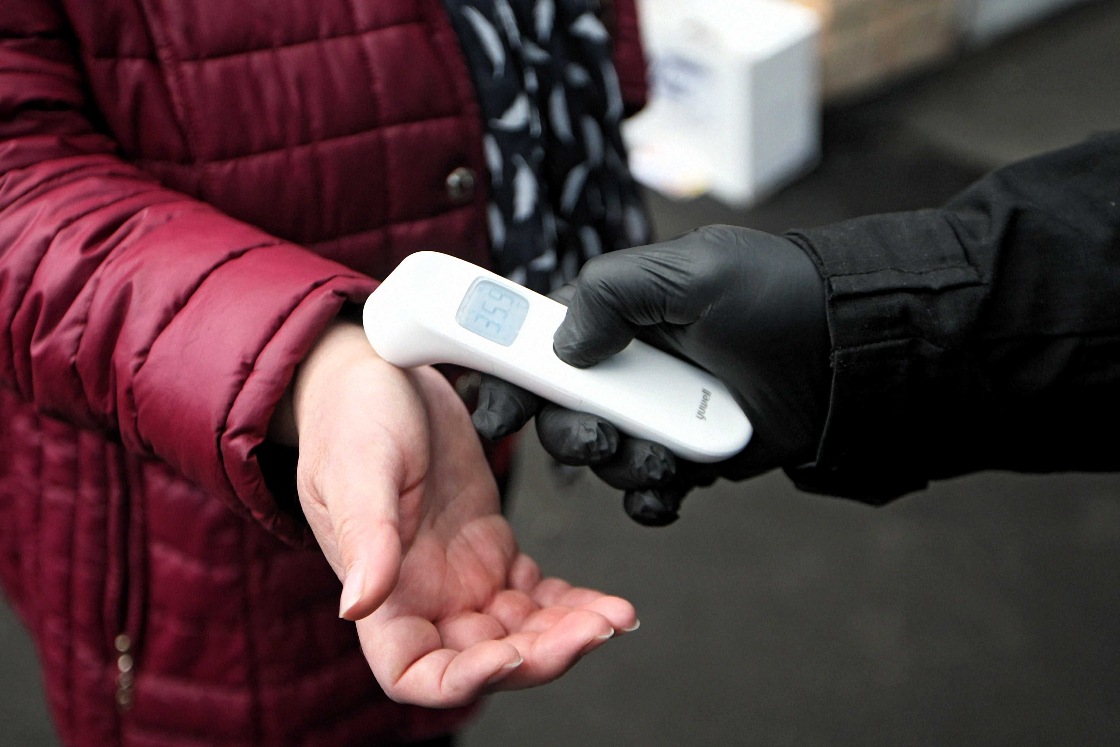 A woman’s body temperature is read with a contactless thermometer.