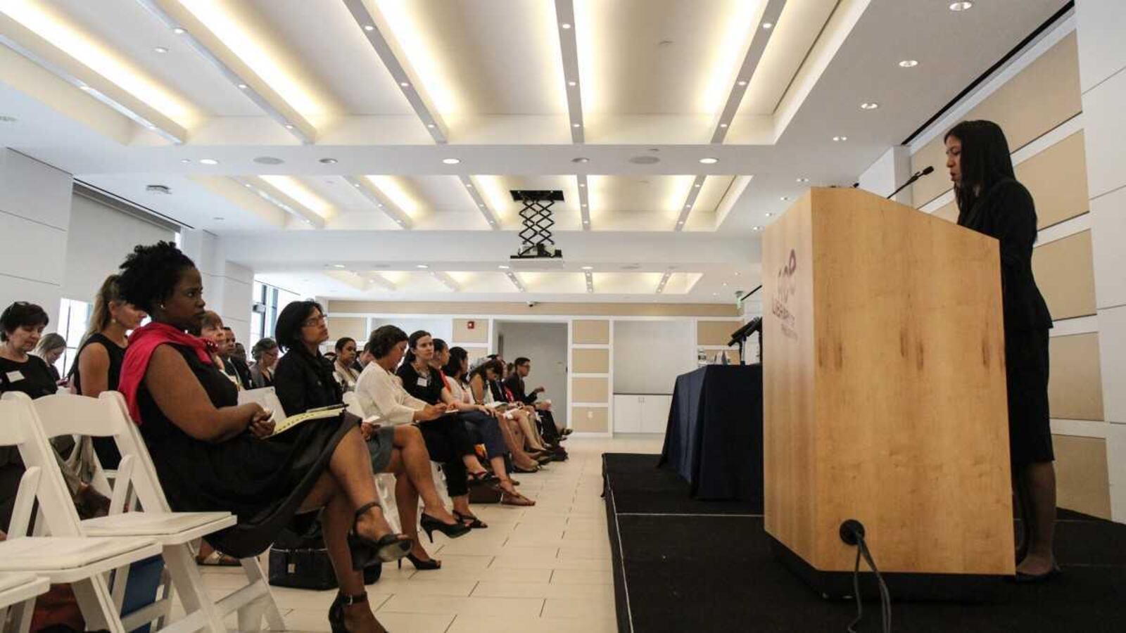 Kristine Alvarez speaking at a podium.