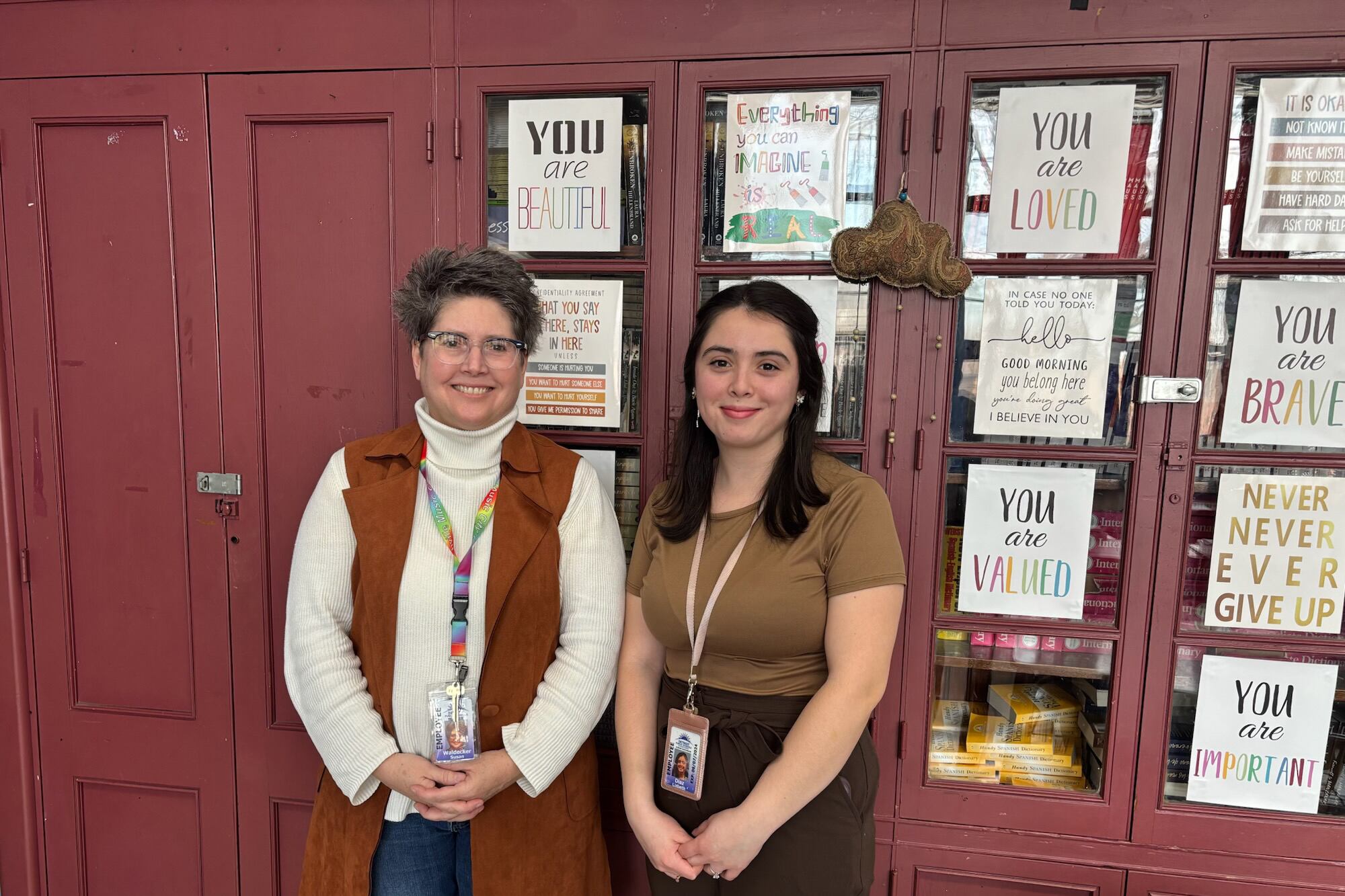 Two people stand together for a portrait in front of a red door.
