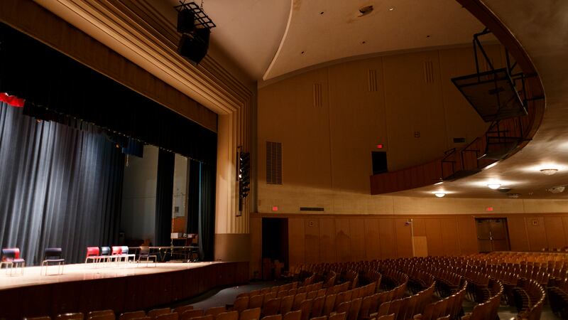 A high school auditorium with a view of the stage and seat rows.