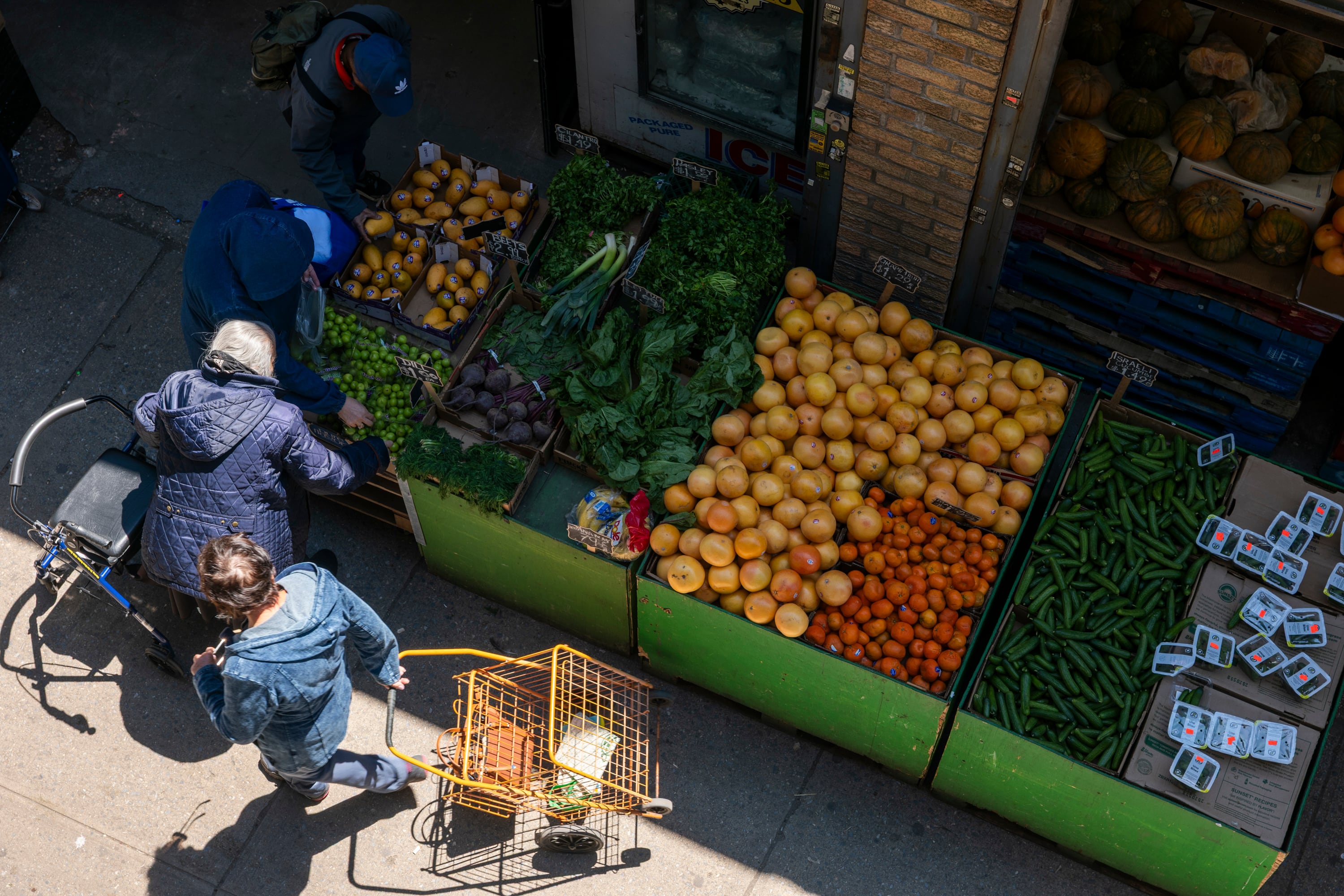 A bird's-eye view of a grocery stand on the street where people are picking food.
