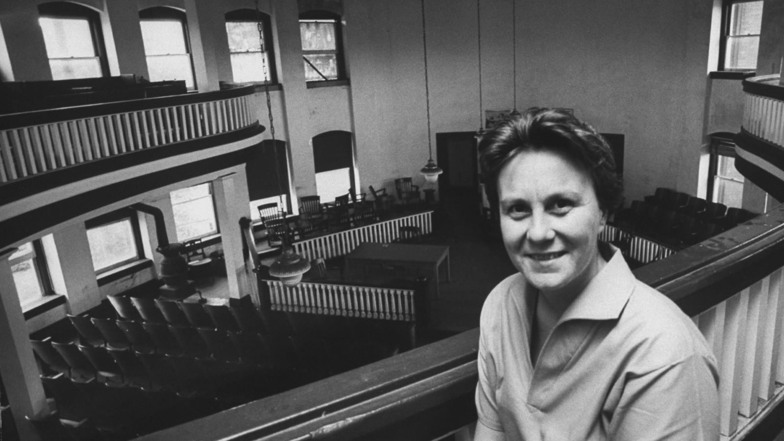Harper Lee sitting in an upper balcony of a court house.