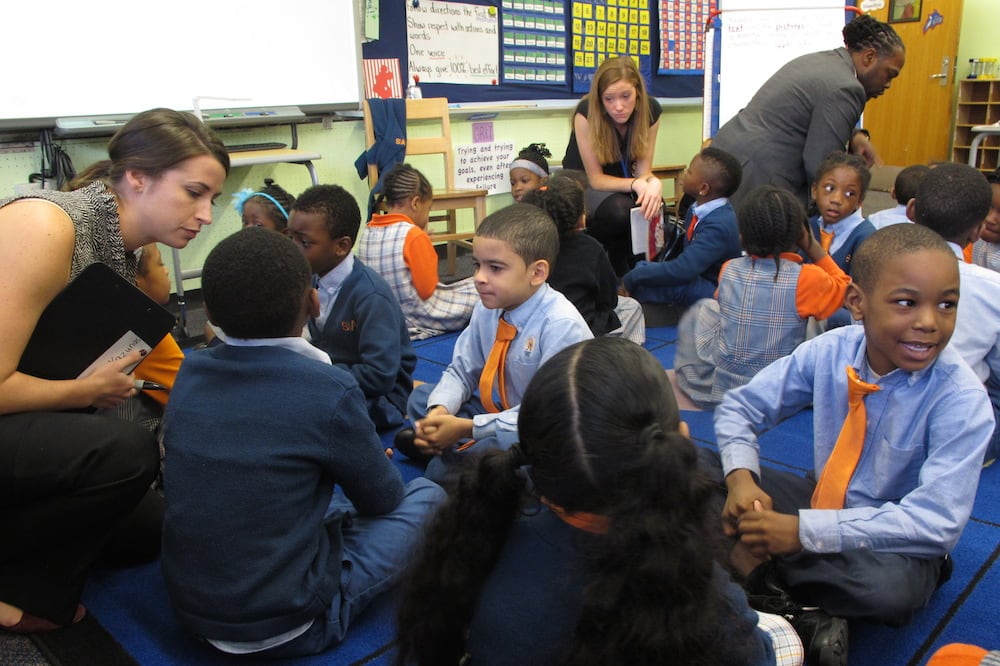 Students wearing blue button down shirts and orange ties sit