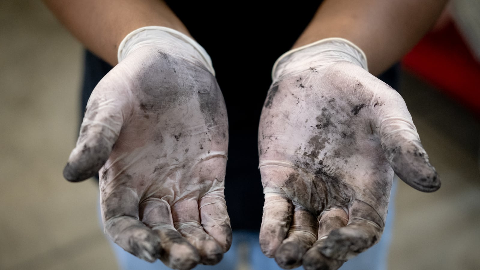 A young man shows black ink on his latex gloves.