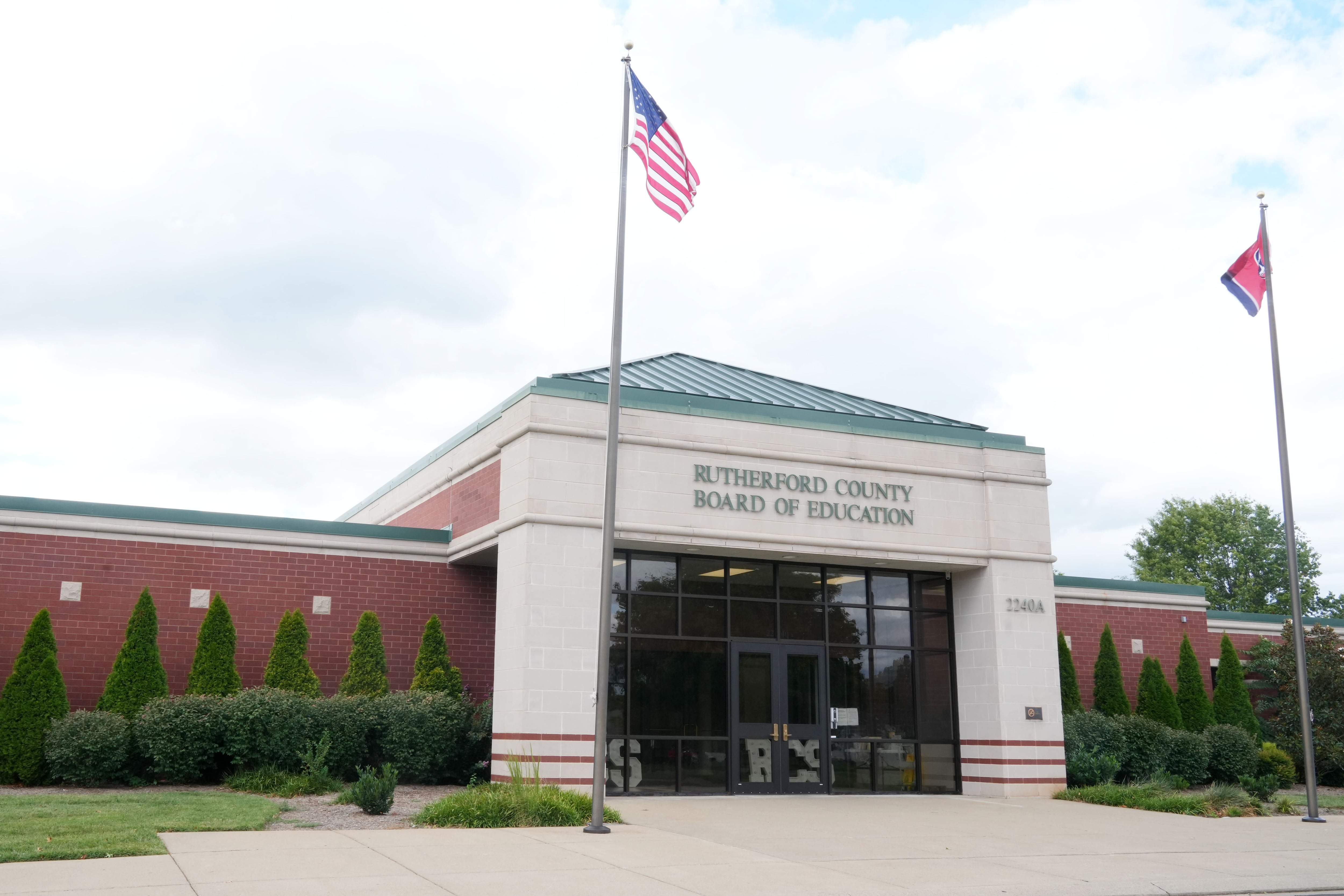 A white building with green roof and a flag.