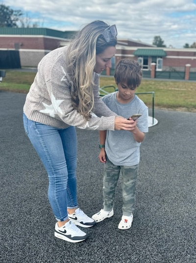 A boy and his mom look at a cellphone.