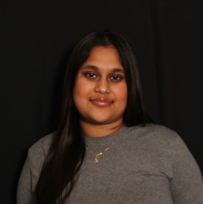 Headshot of a teenage girl with black hair. She wears a gray sweater.