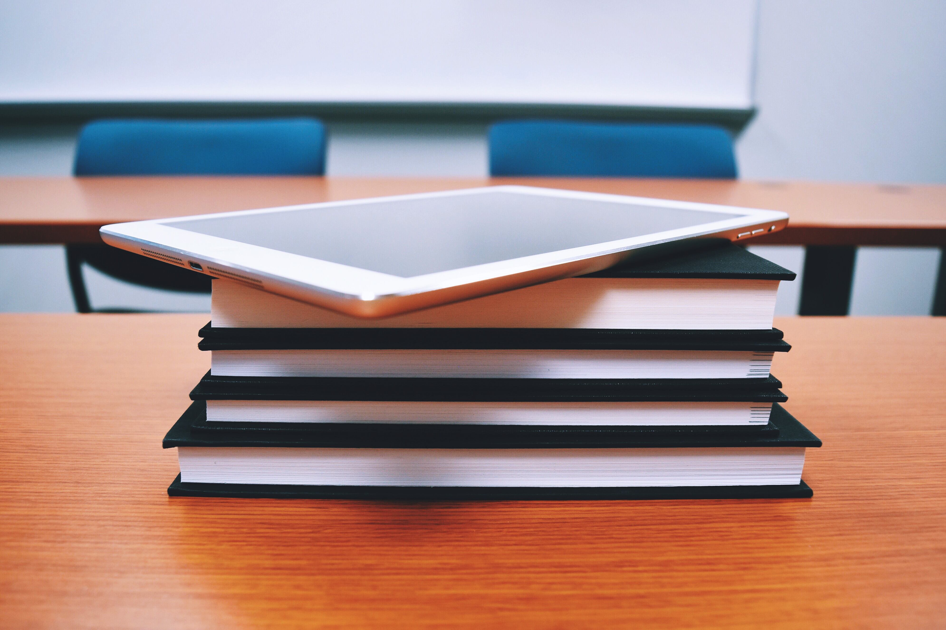 A tablet on top of a stack of books.