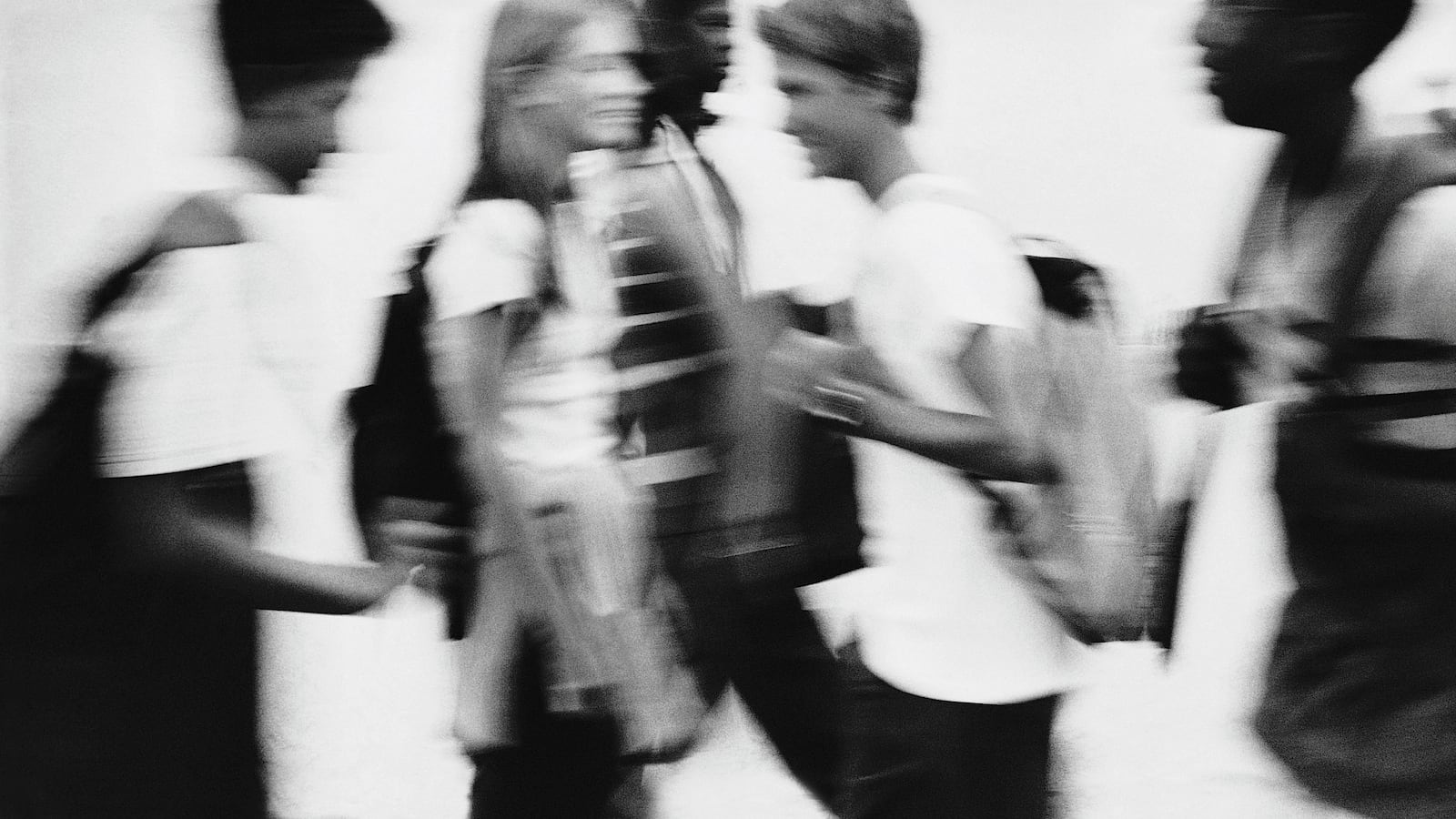 Black and white photo of high schoolers in a hallway.