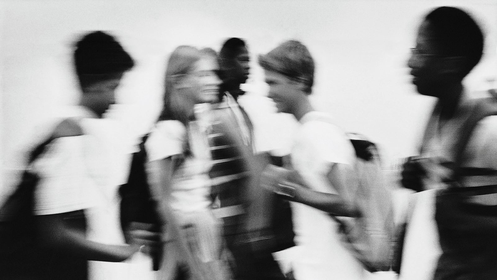 Black and white photo of high schoolers in a hallway.