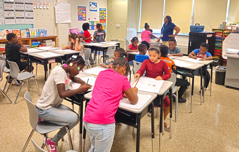 A group of students sit at their desks in a classroom.