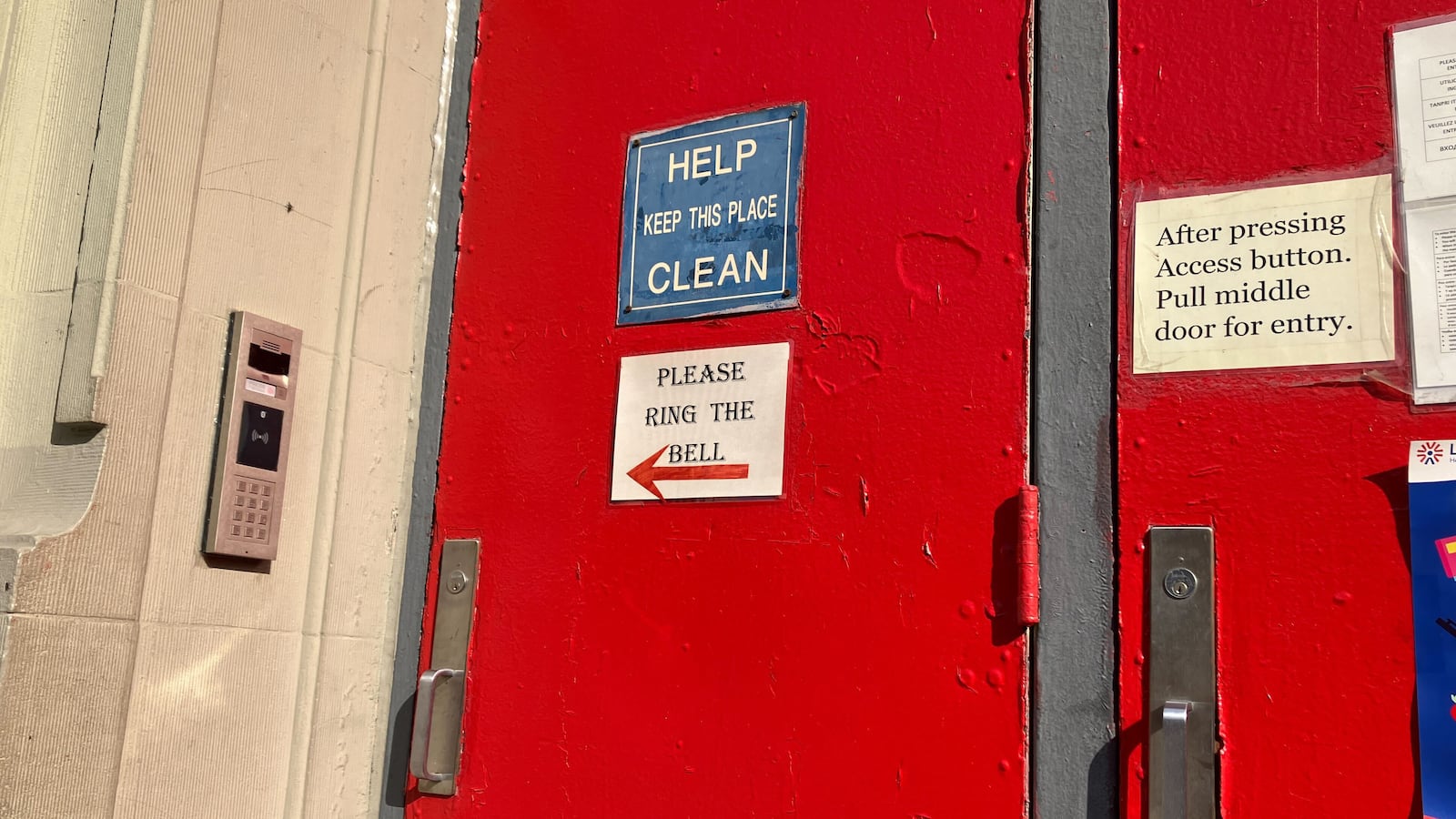 Signs are posted on a red door.