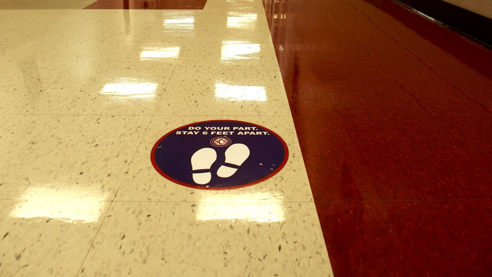 A sticker urging social distancing was placed in a school building hallway
