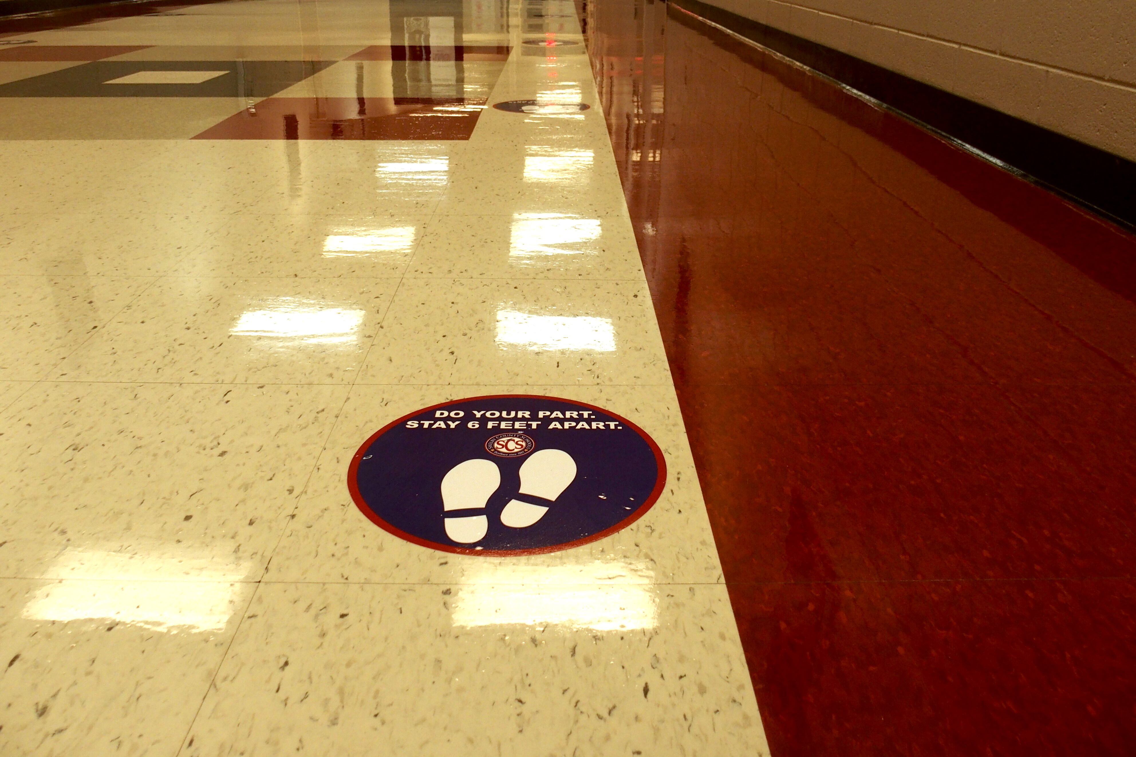 A sticker urging social distancing was placed in a school building hallway
