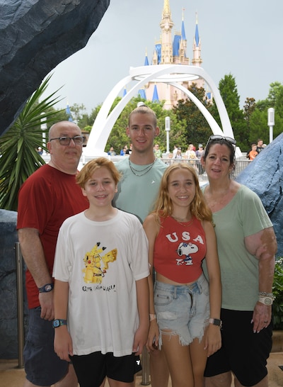 A family of five stand next to each other while they smile and pose for a photograph.