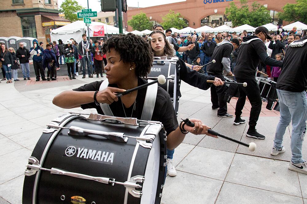 A student performs in a drumline in a courtyard.