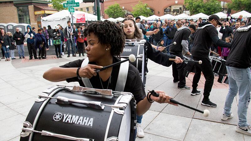 A student performs in a drumline in a courtyard.