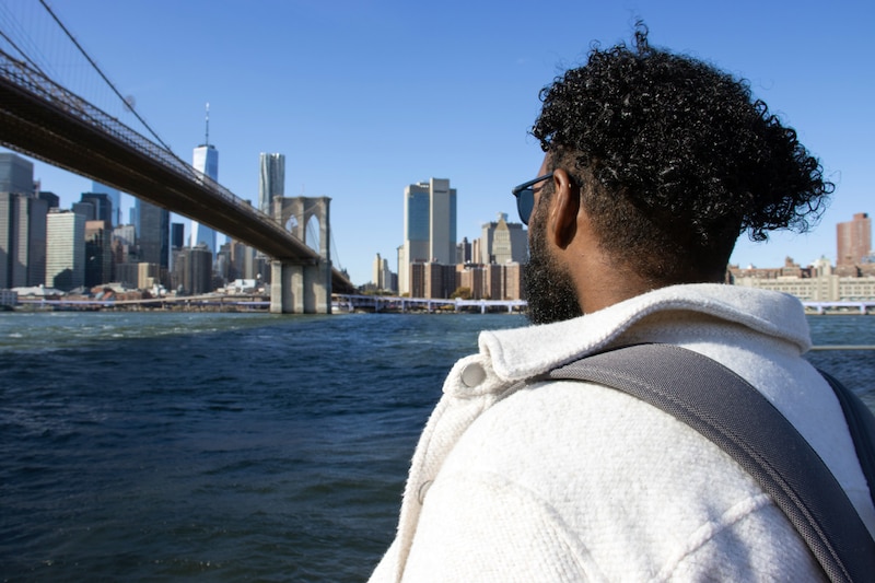 A view of the back of a student looking across the East River with the New York City skyline in the background.