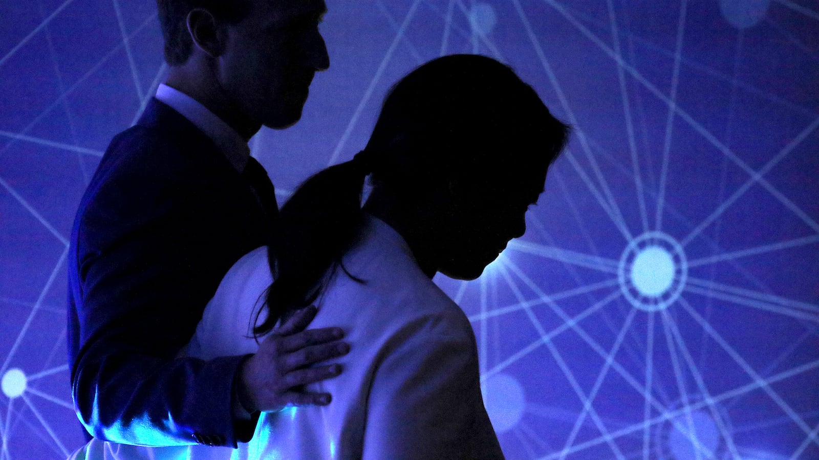 Two people are silhouetted next to a purple screen with white lines