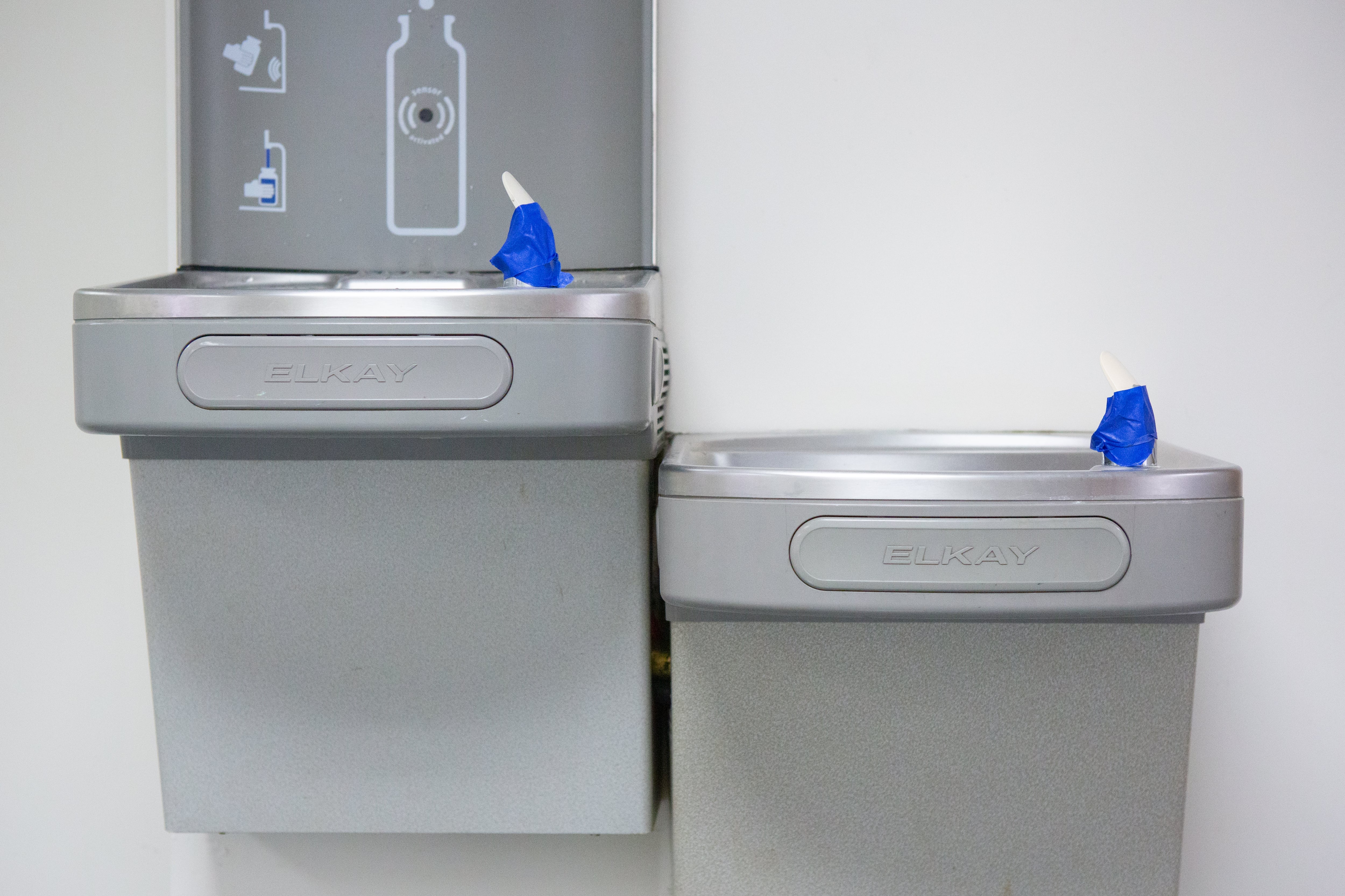 Drinking fountains with tape over the spouts to prevent use.