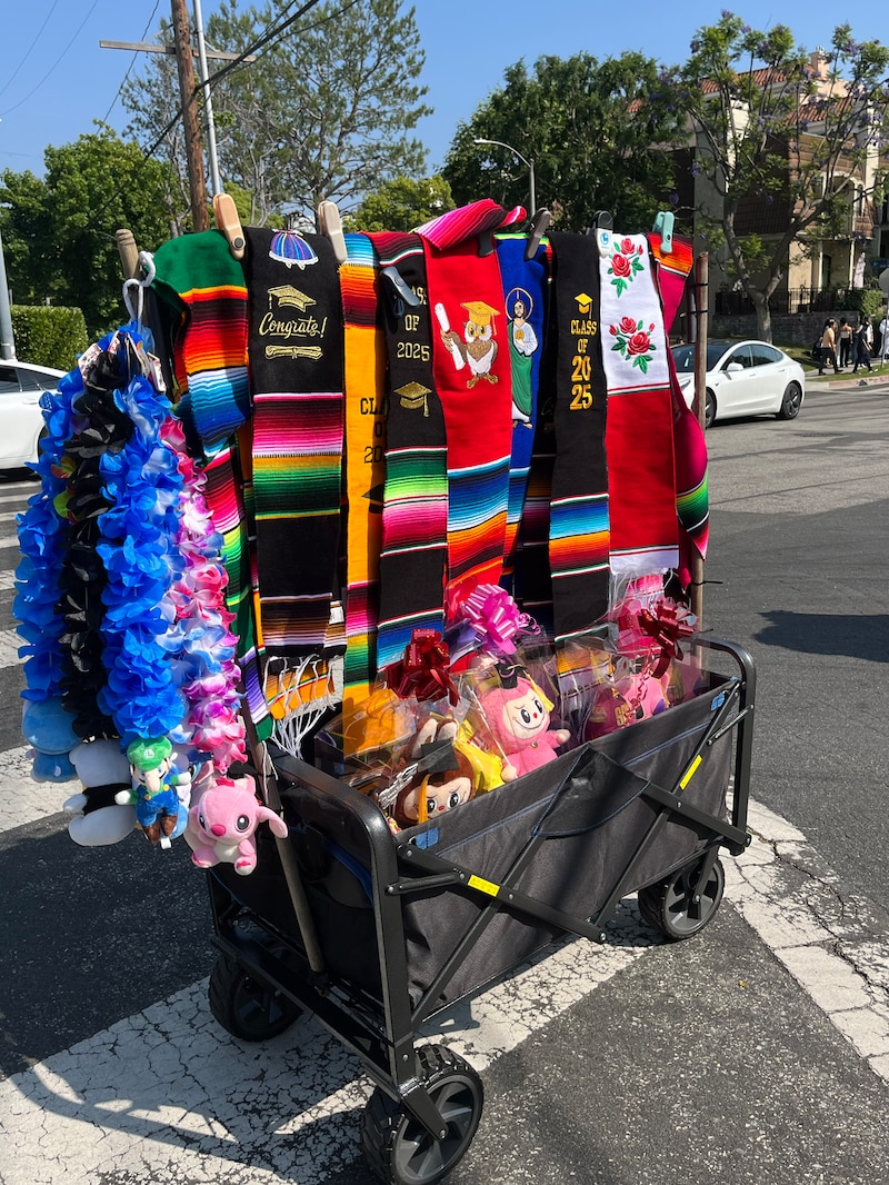 Mexican sarapes or graduation sashes and colorful leis hang on a moveable cart outside.