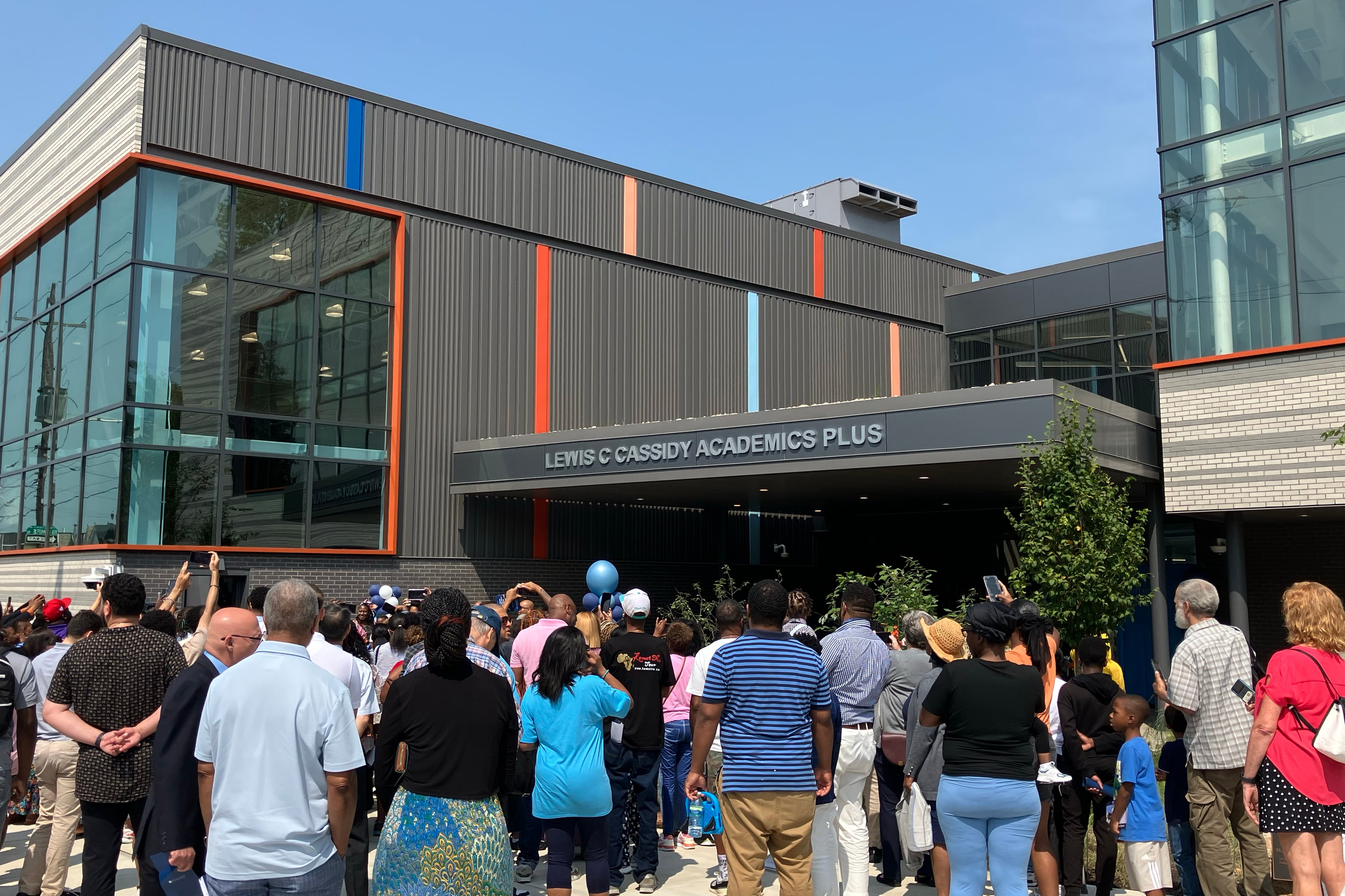 A group of people stand outside the entrance of a school.