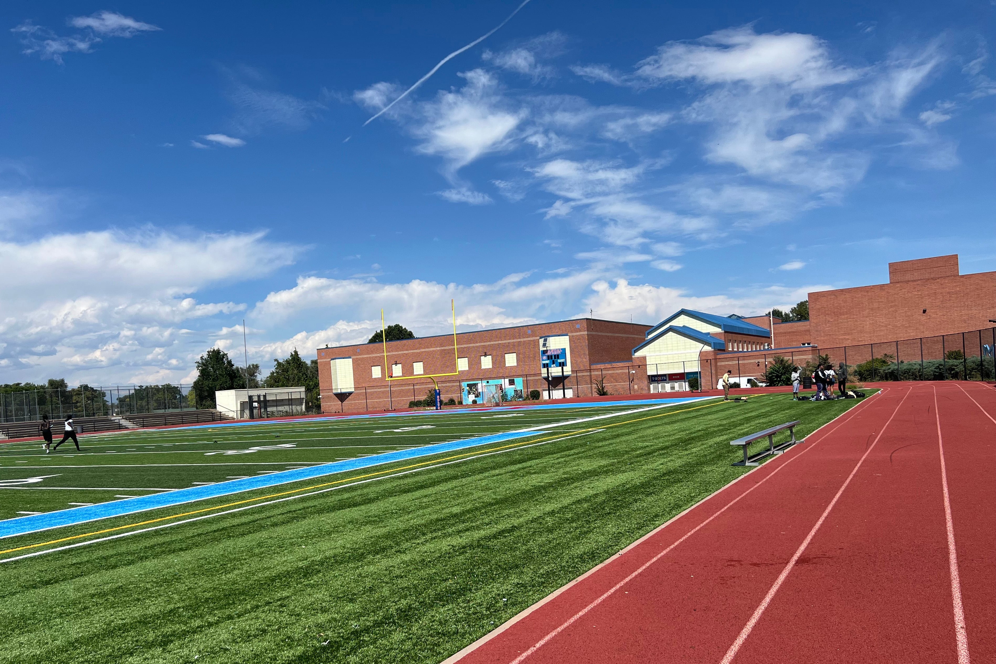 An exterior photo of a high school with a track and playing field.