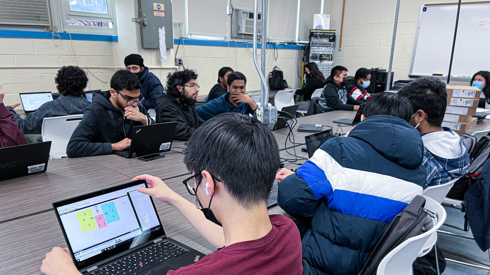 Students sitting at a table at school working on computers.