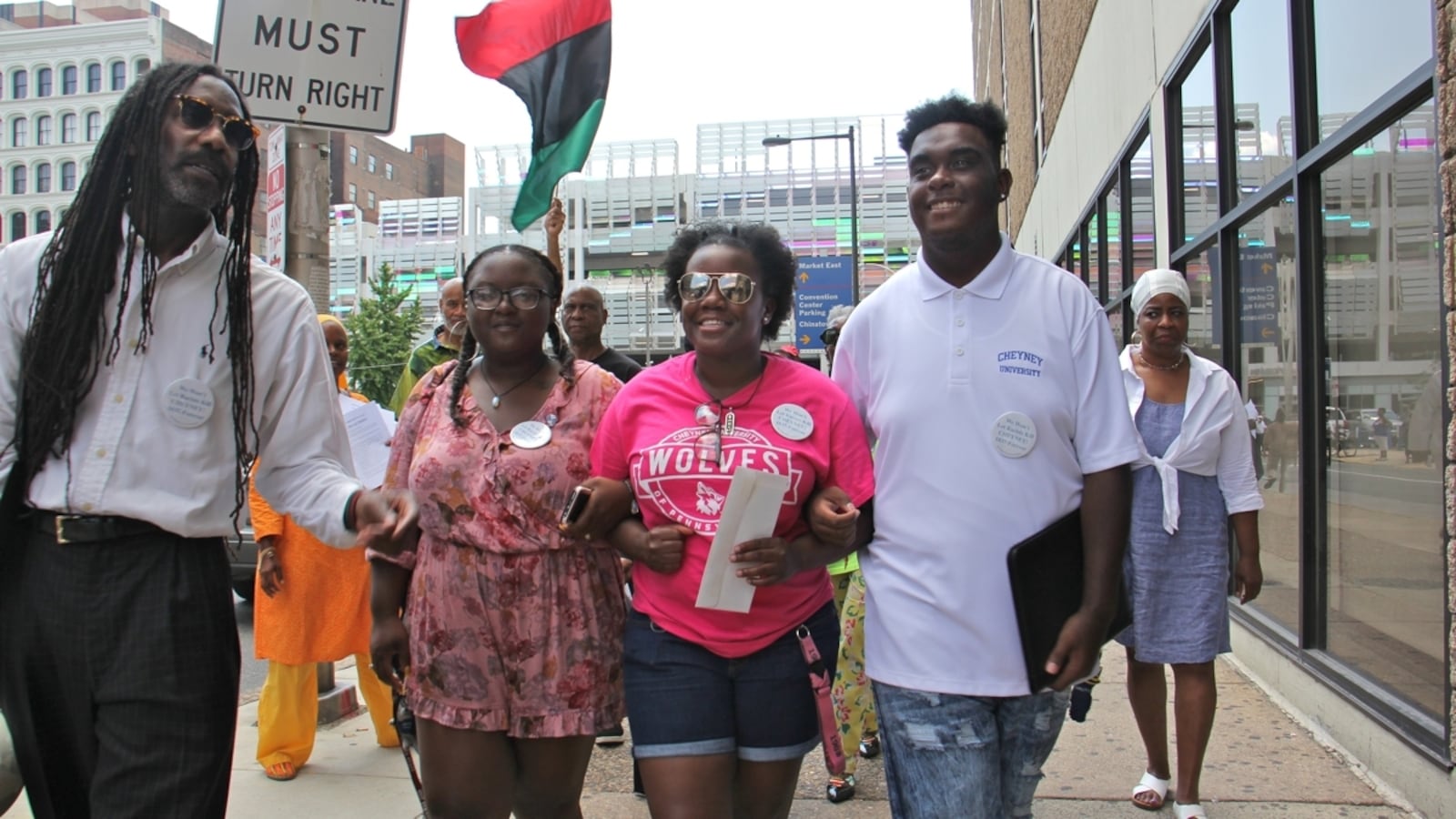 Cheyney students (from right) Shaquille Harrison, Nyrie Watson and Shaneka Briggs link arms as they make their way to Gov. Tom Wolf's Philadelphia office on Eighth Street to deliver a letter demanding funds for the struggling historically black university.