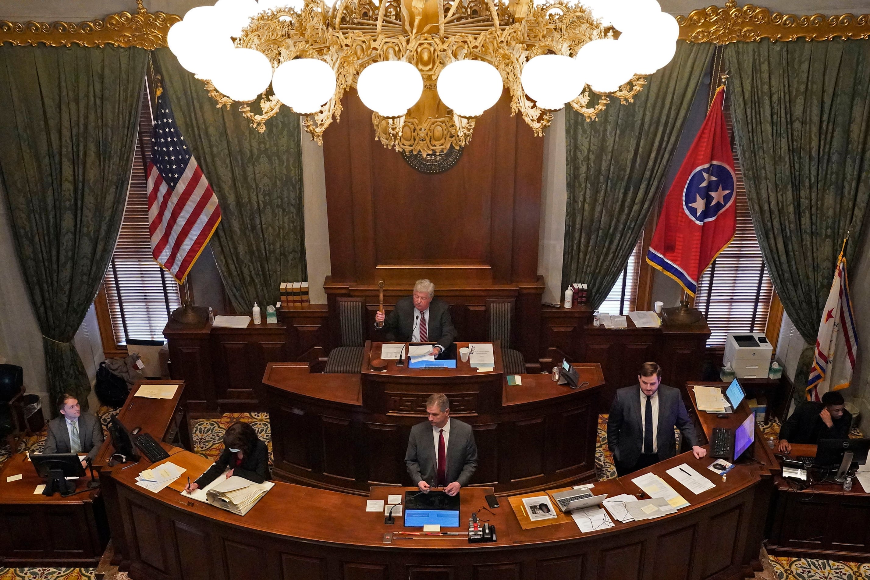 People work in an ornate legislative chamber.