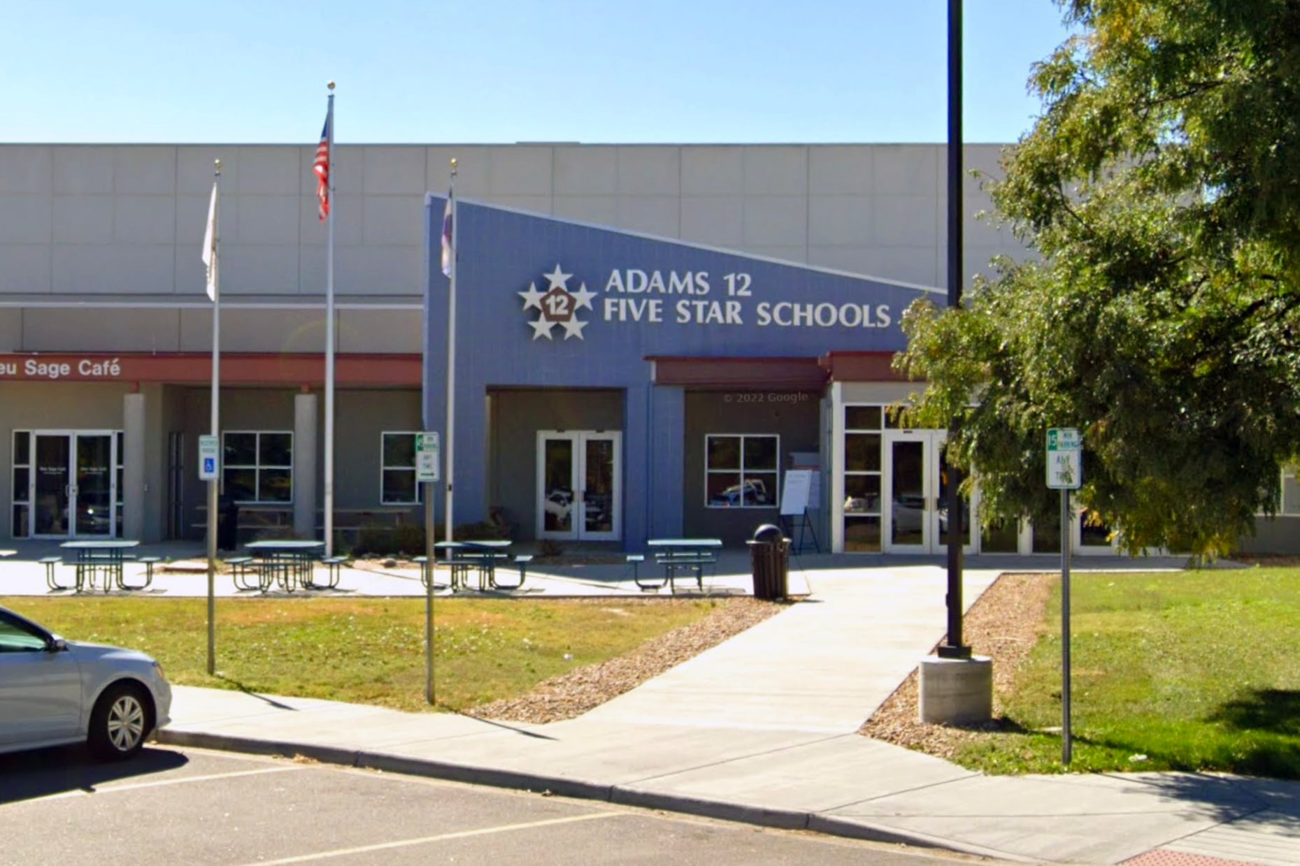 Photo shows Adams 12 Five Star Schools district offices in Thornton. The blue entryway has a sharp angle with a large sign with the district name.