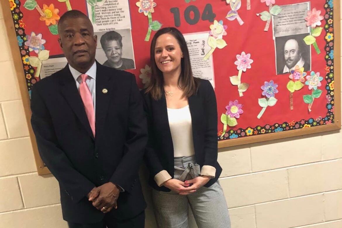 A man and a woman stand in front of a school bulletin board.