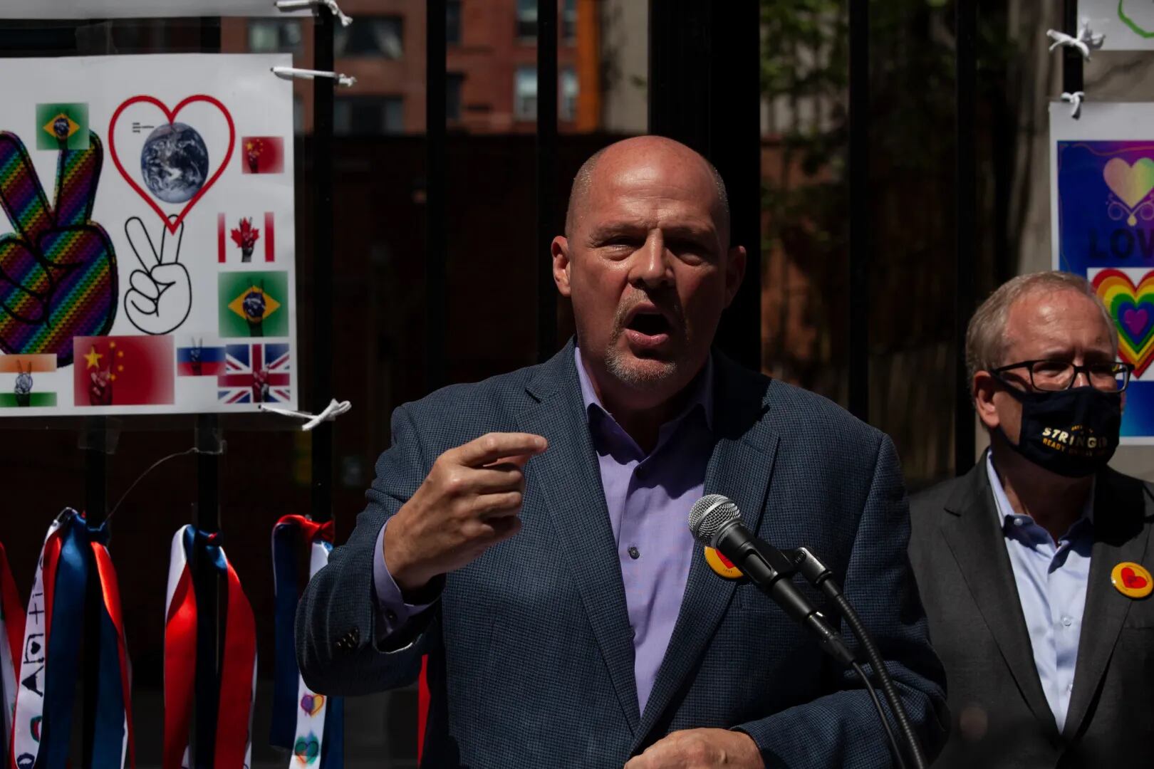 A man in a gray suit without a tie talks at a podium.