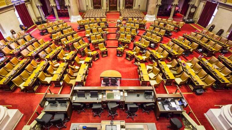 An overhead view of the NY Assembly room with red carpets and rows of yellow chairs