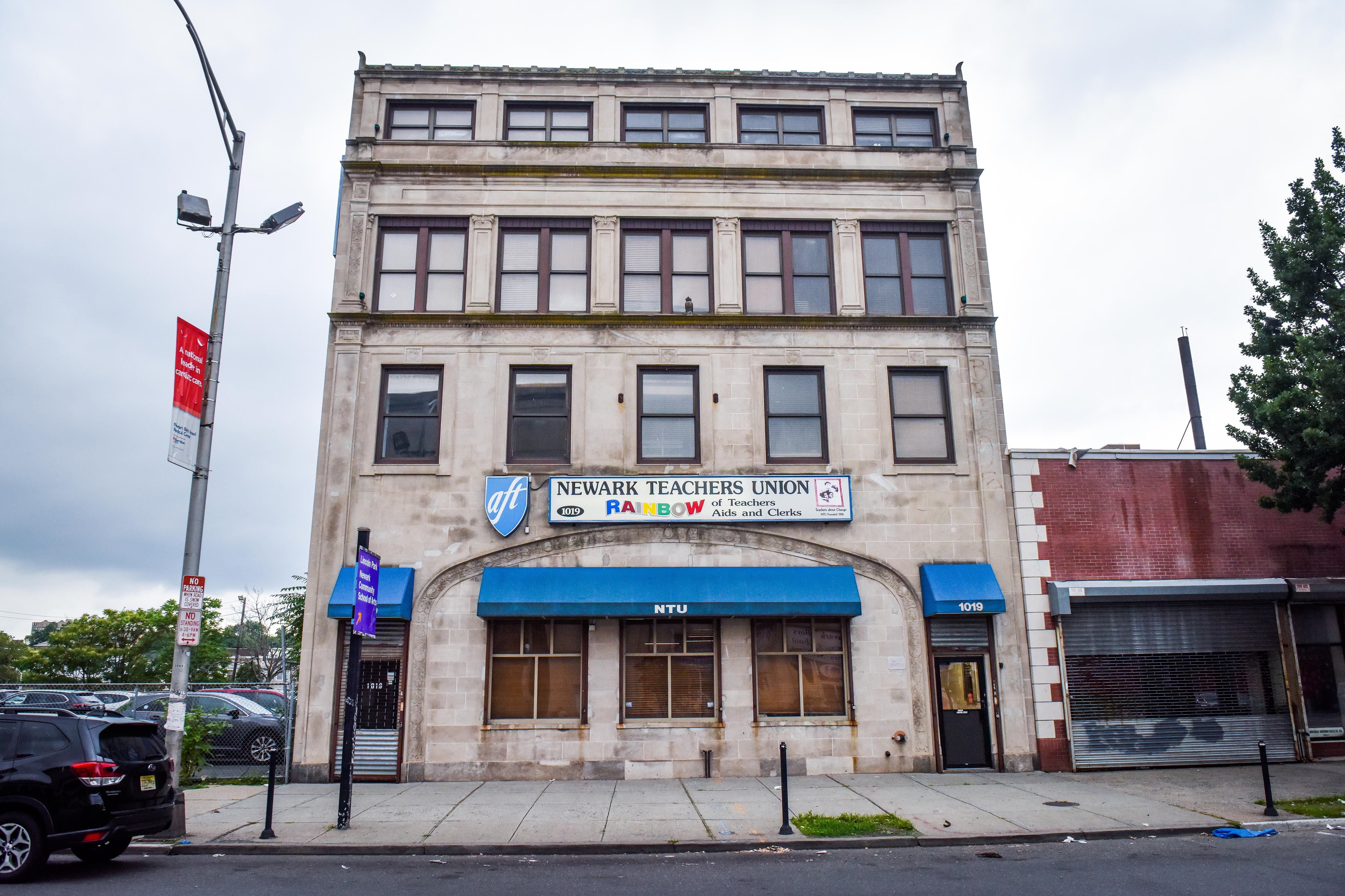 A white building is seen with a blue canopy and a sign that reads “Newark Teachers Union”