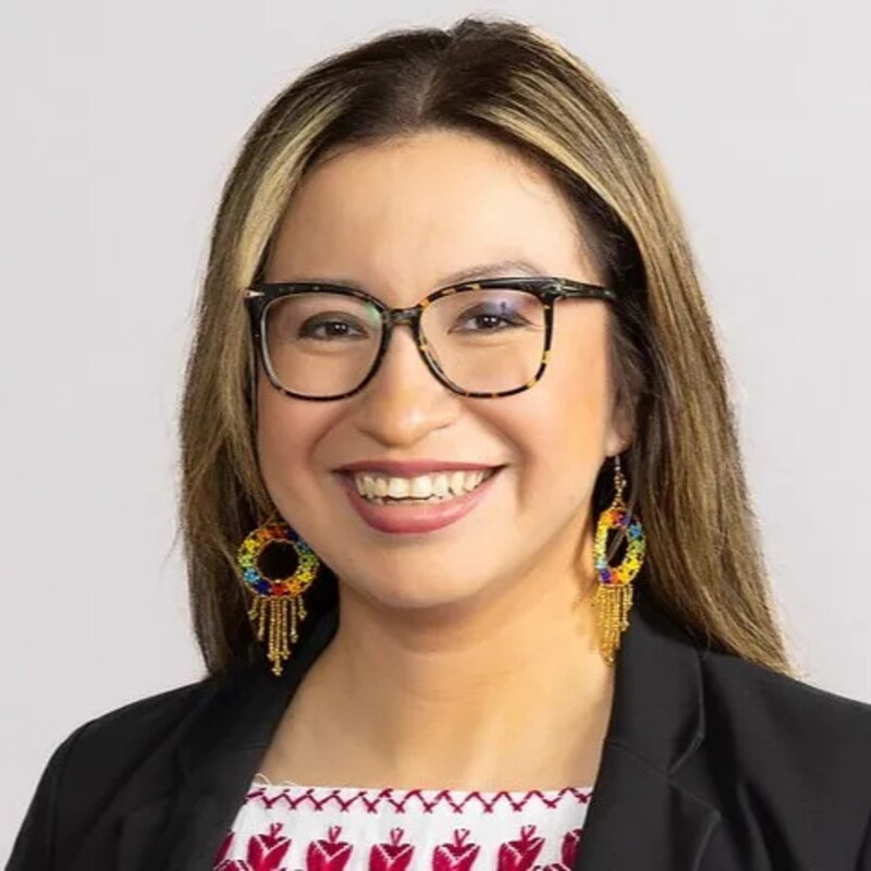 A portrait of a woman with glasses and a dark jacket.