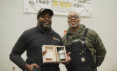 Two Black men stand side by side smiling for a portrait.