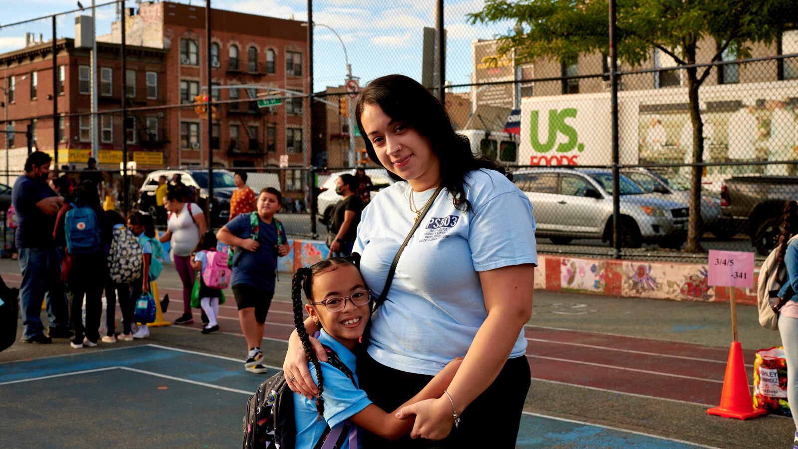 A mother poses for a portrait with her daughter on a court during the first day of school.