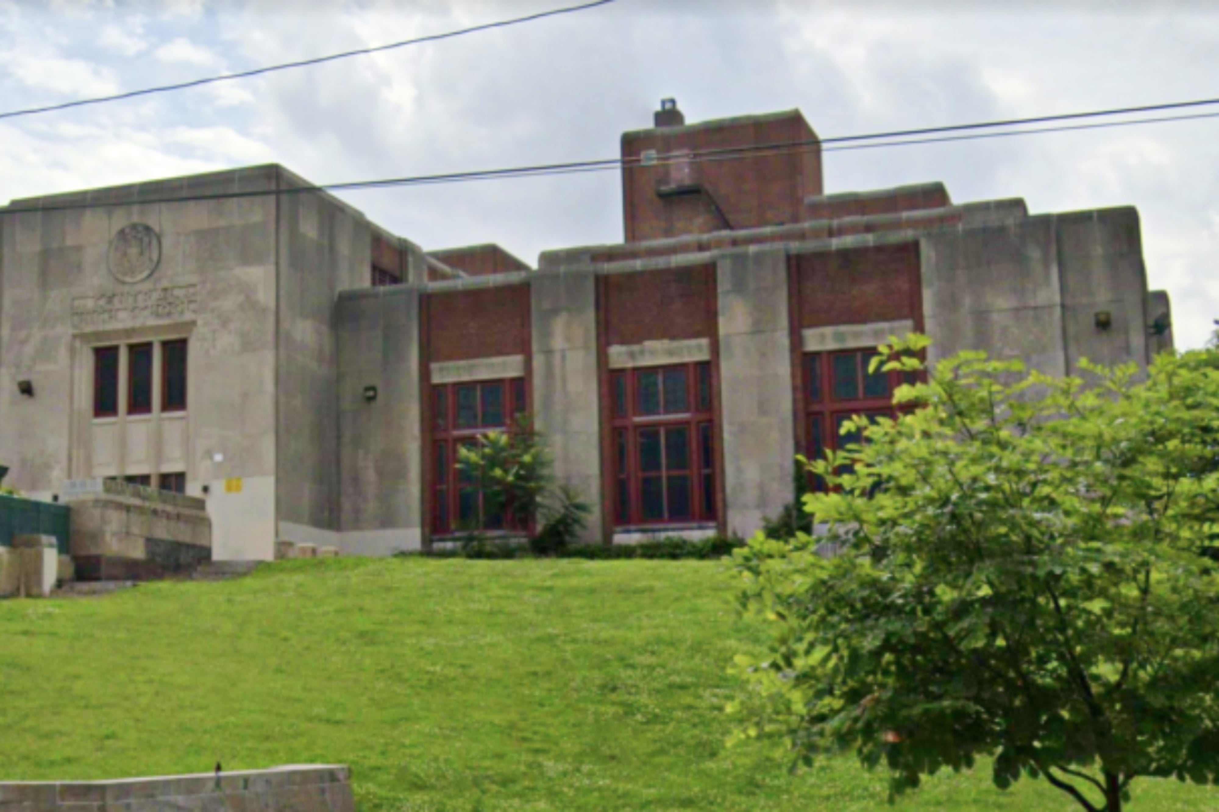 The concrete and brick building of Central High School in Philadelphia with a lawn in front of it.