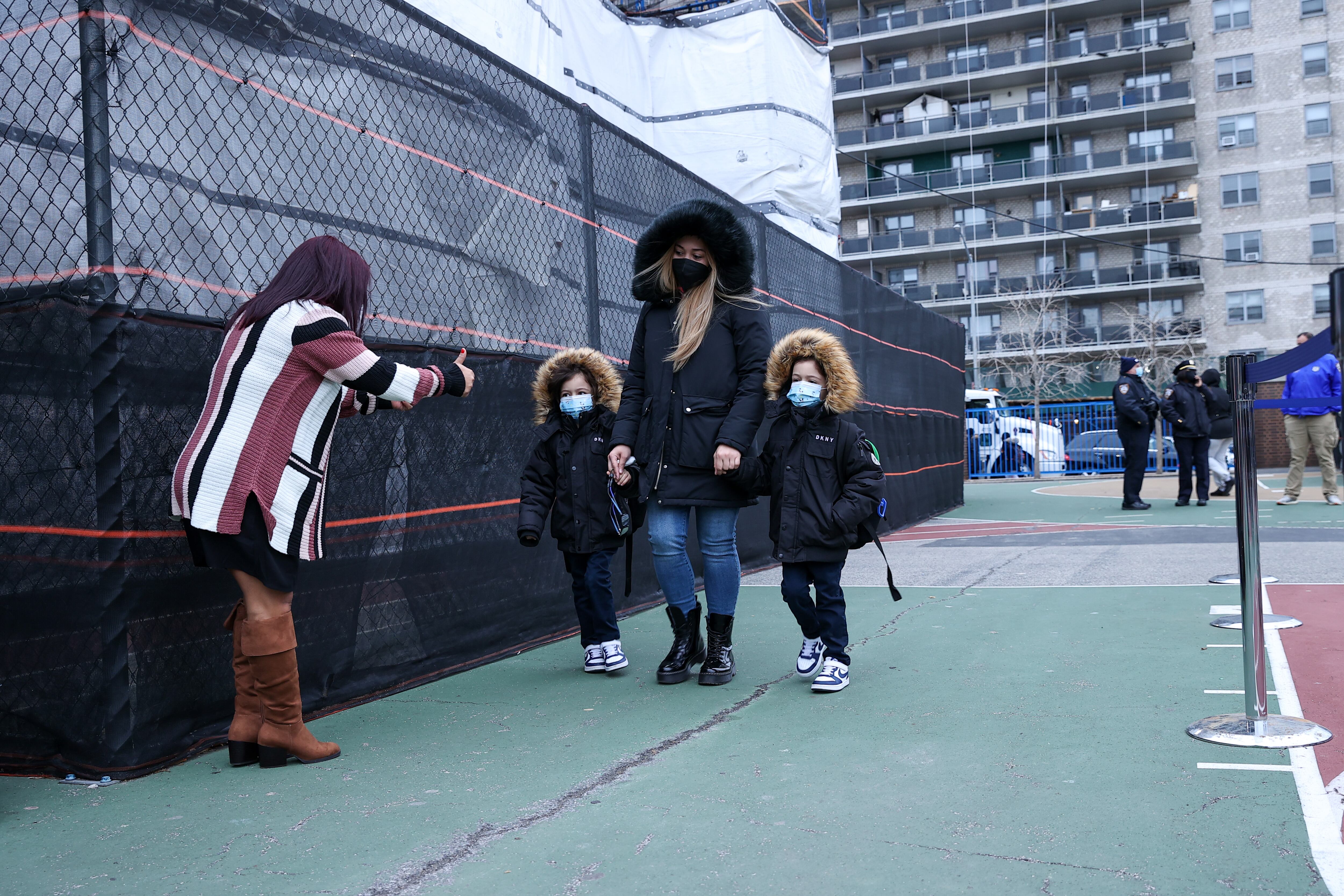 An adult approaches an elementary school with two children in winter coats.